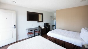 A hotel room with a bed, a desk with a chair, a television, and a coat rack.