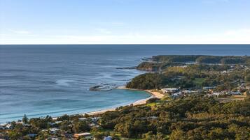 Uma cidade costeira com praia, vegetação densa e edifícios residenciais.