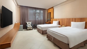 A hotel room with two beds, a TV, a desk, a chair, and a window with curtains. - Days Inn by Wyndham Chiayi (Taibao)