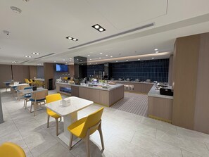 Un comedor moderno de hotel con una isla central, diversas opciones de asiento y una pantalla de televisión.