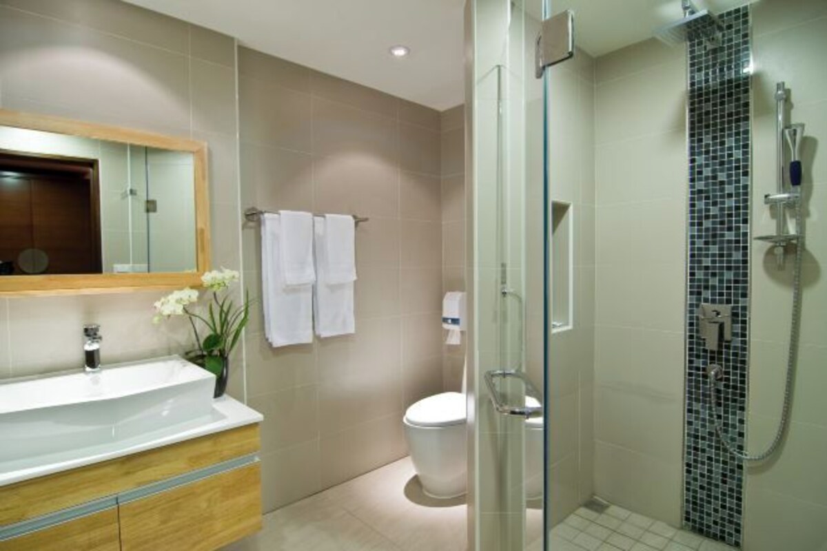 A bathroom with a sink, mirror, toilet, and shower.