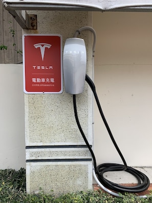 Una estación de carga de Tesla con un letrero rojo y un dispositivo de carga blanco.