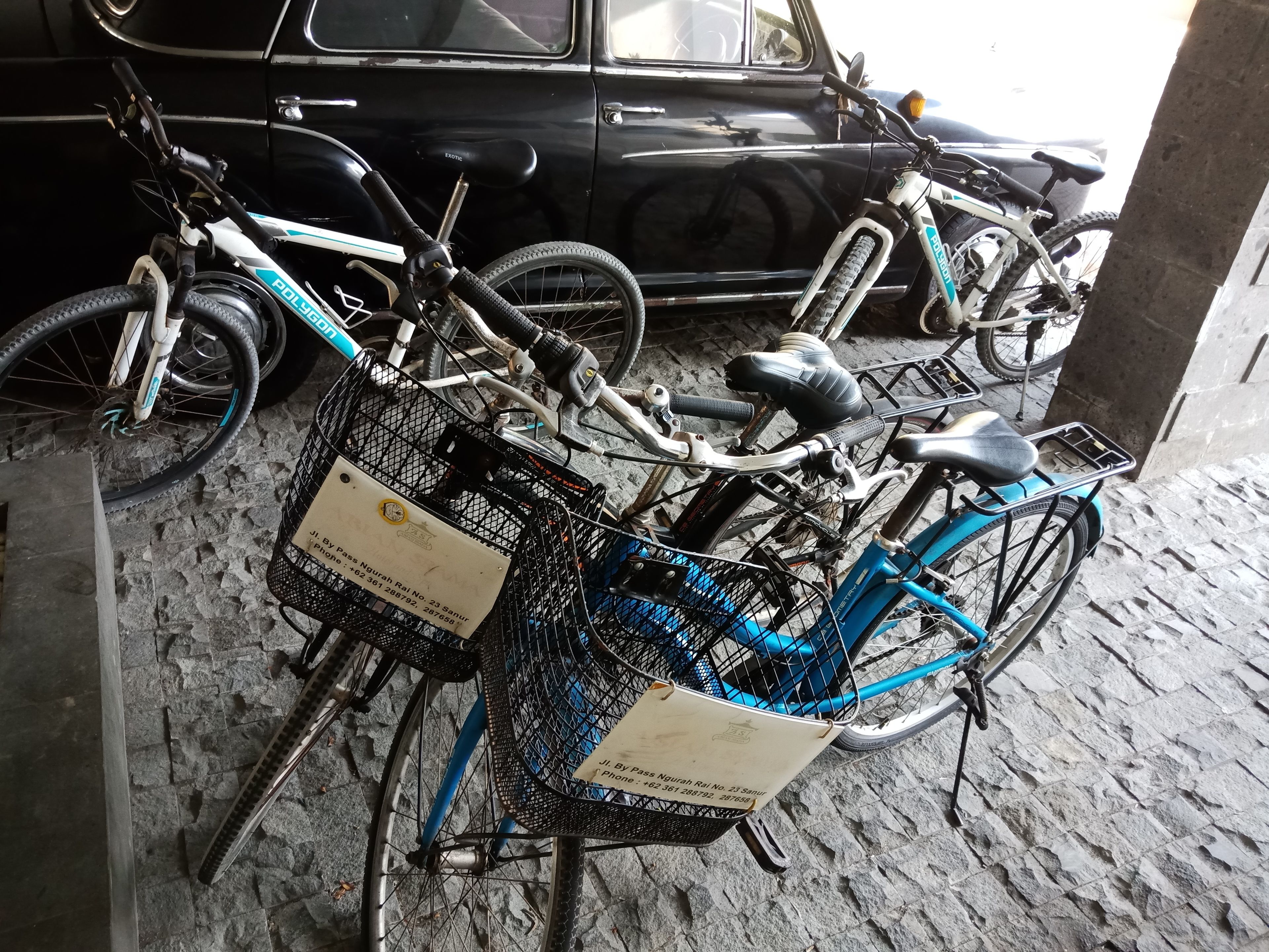 A bicycle with a basket and a tag attached to it, parked in a garage.
