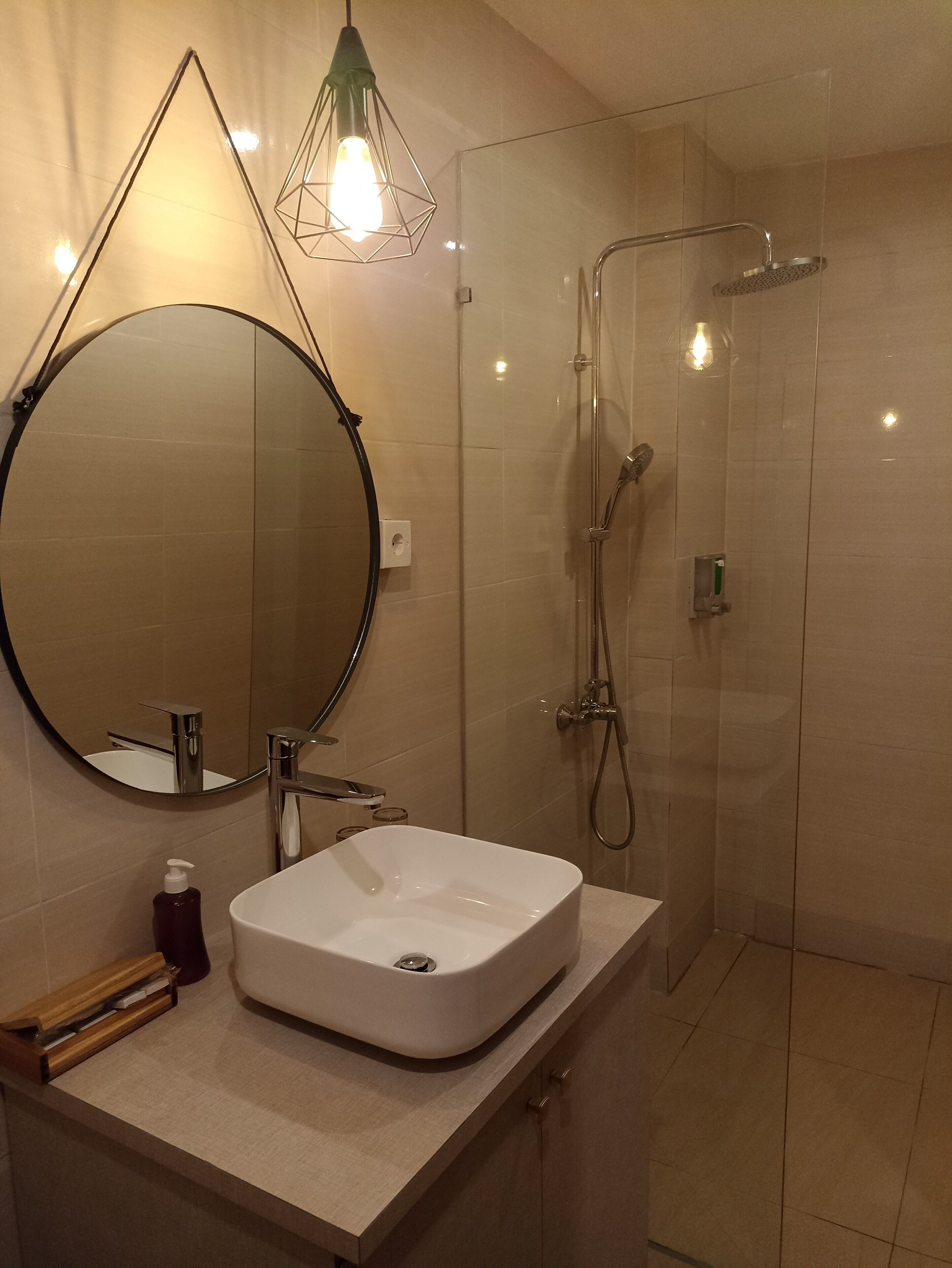 A modern bathroom with a round mirror, a rectangular sink, and a glass-enclosed shower.