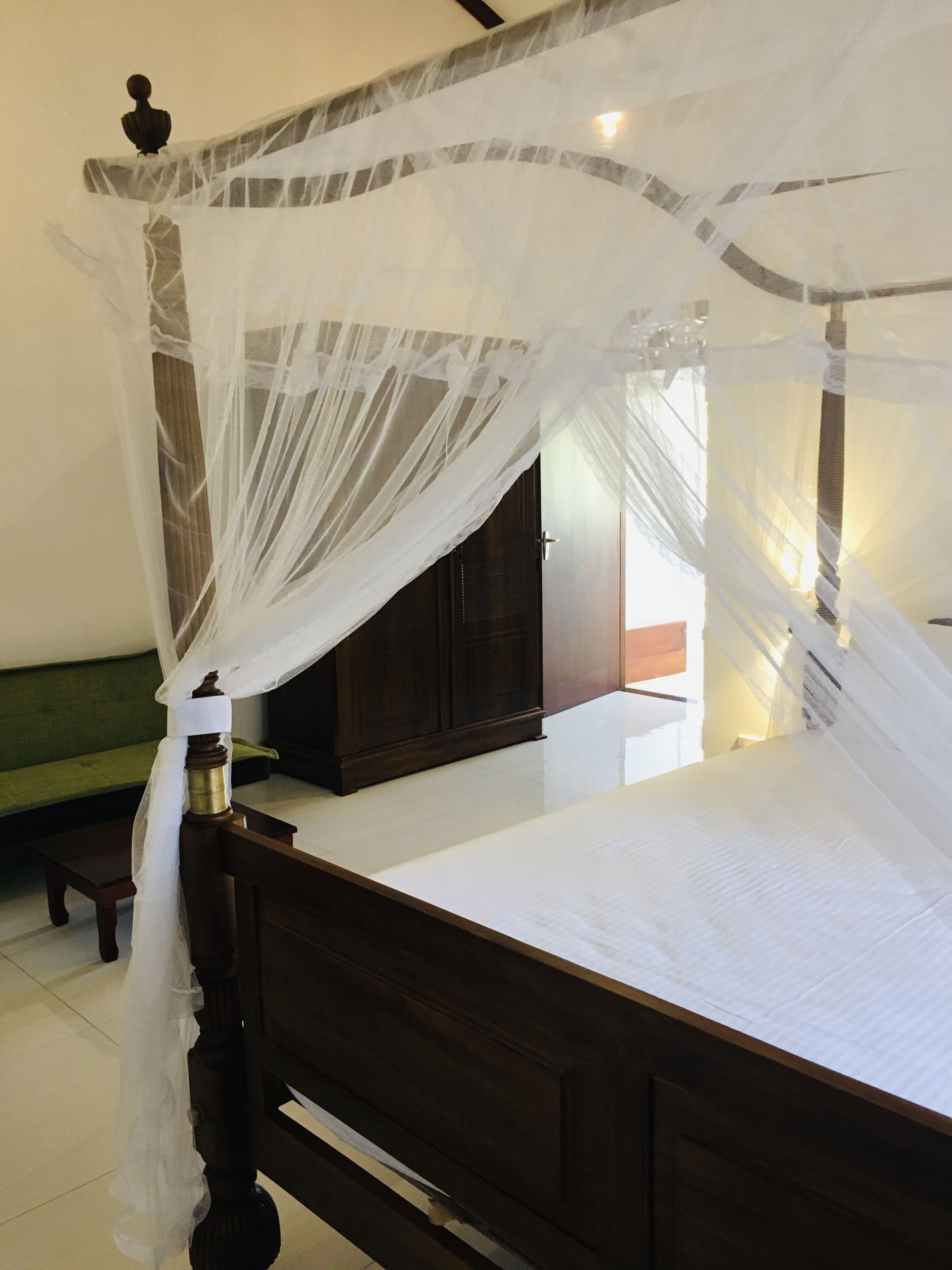 A bed with a wooden frame and a white canopy.