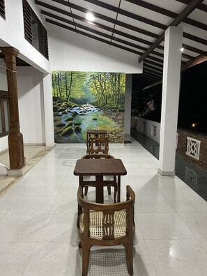 A dining area with a table and chairs, a mural of a forest stream, and a view of the outdoors.
