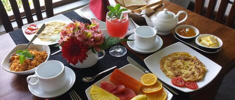 Una mesa de desayuno con diversos platos, entre ellos tostadas, fruta y un hervidor de agua.