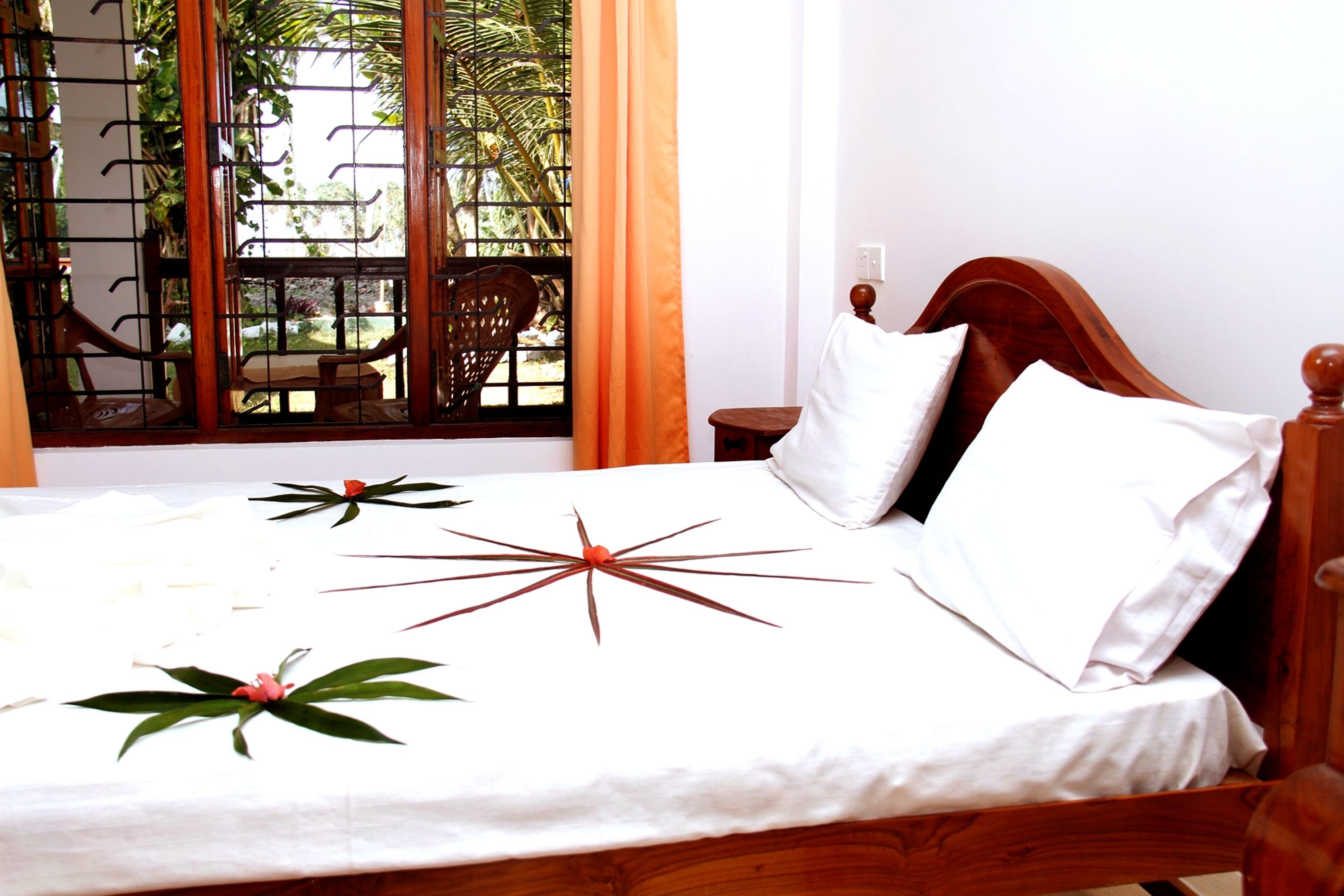 A neatly made bed with a star-shaped decoration, a wooden headboard, and a window with a view of greenery.