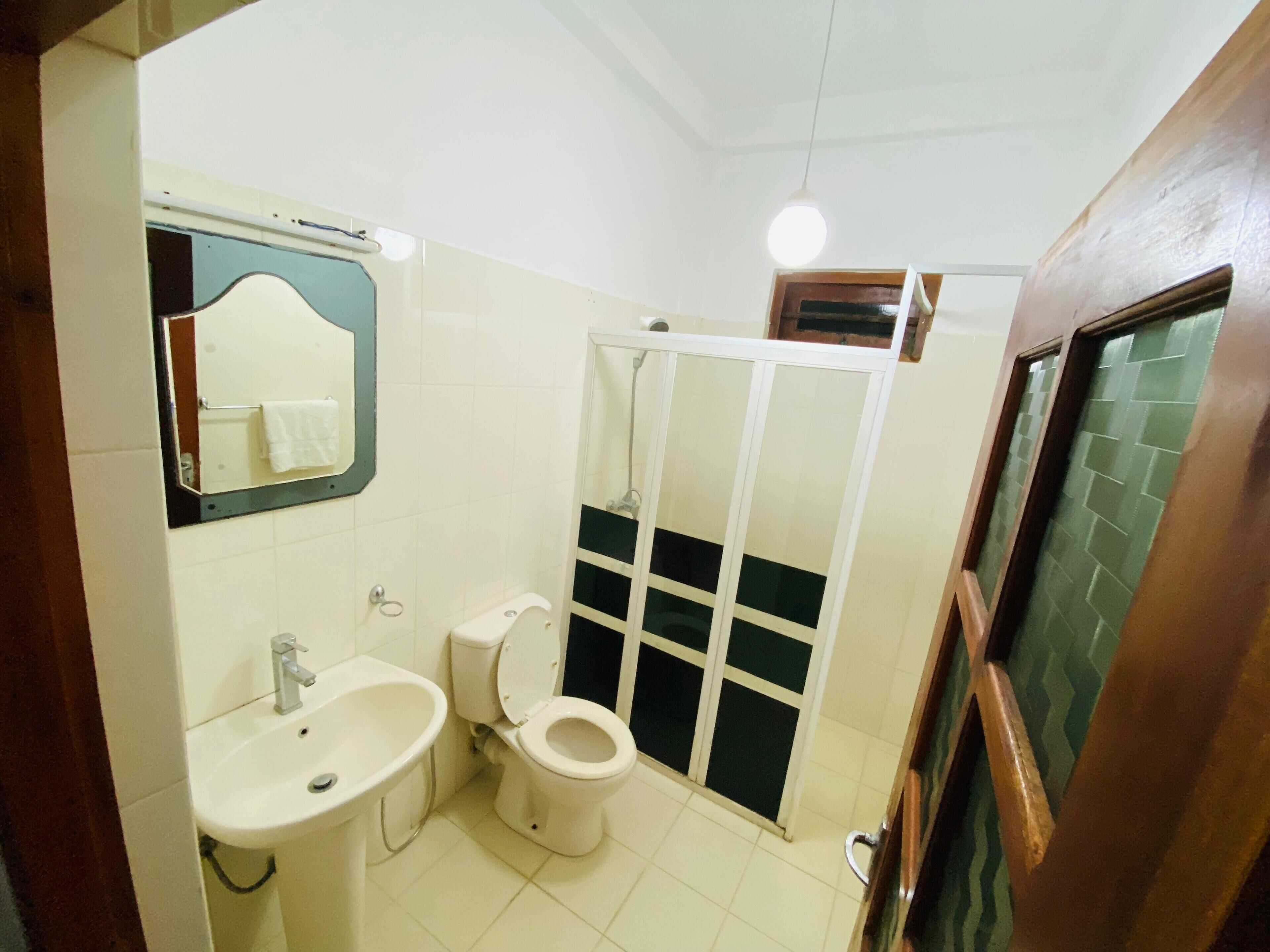 A bathroom with a sink, toilet, and a shower enclosure.