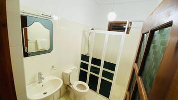 A bathroom with a sink, toilet, and a shower enclosure.