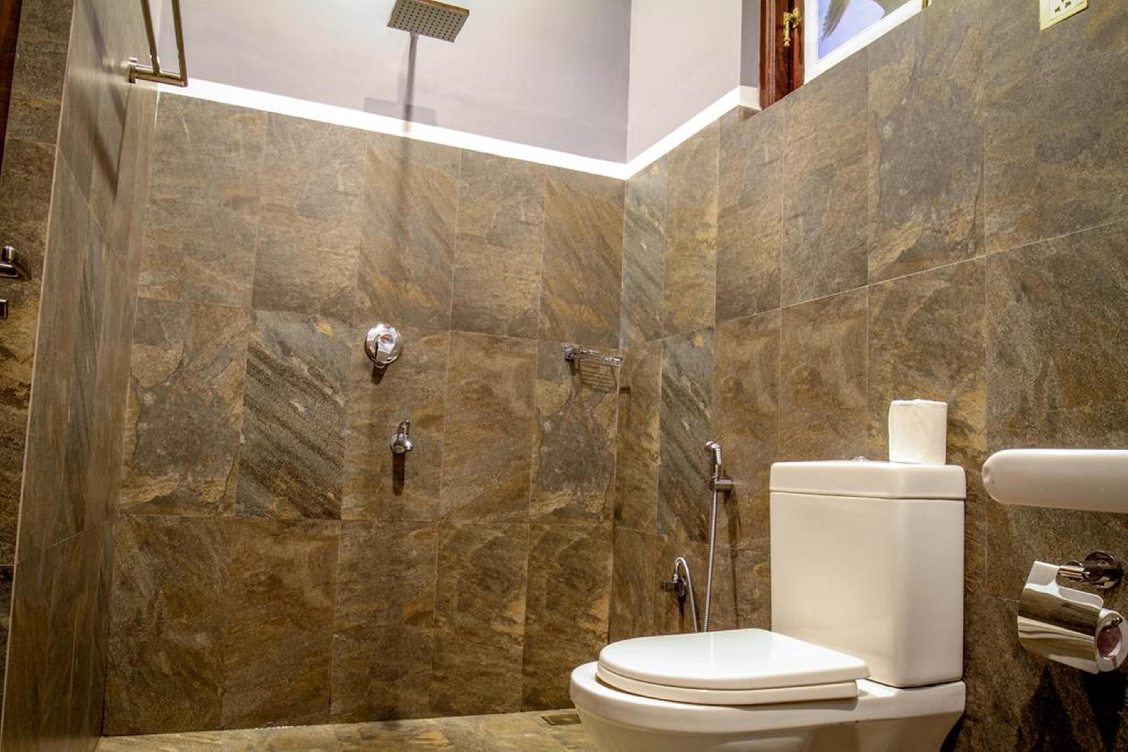 A bathroom with a shower, toilet, and a towel dispenser.