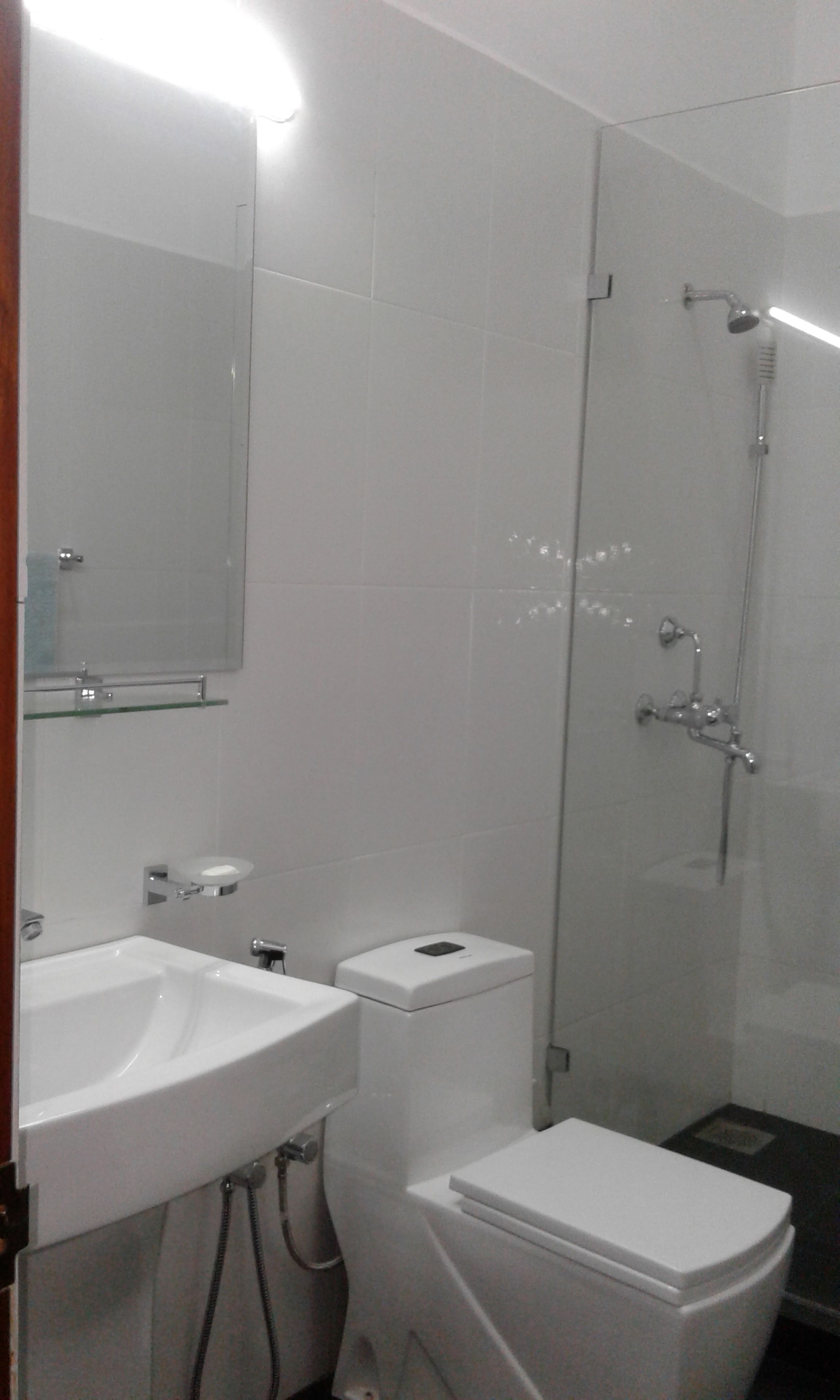 A bathroom with a white sink, mirror, toilet, and glass shower enclosure.