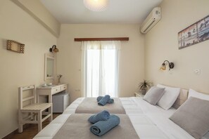 Habitación de hotel con cama, escritorio, silla, mesita, espejo y ventana con cortinas.