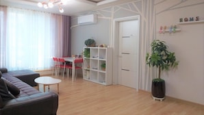 Un salon moderne avec un canapé, une table à manger et des chaises, une bibliothèque et une grande plante en pot.