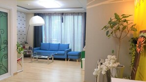 Un salon avec un canapé bleu, une table basse, une lampe et une plante.