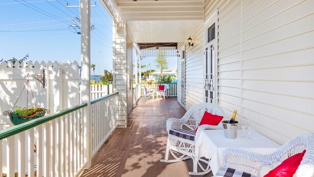 A covered porch with white railings, a wooden ceiling, and a white fence. - Riversleigh Guesthouse (Ballina)