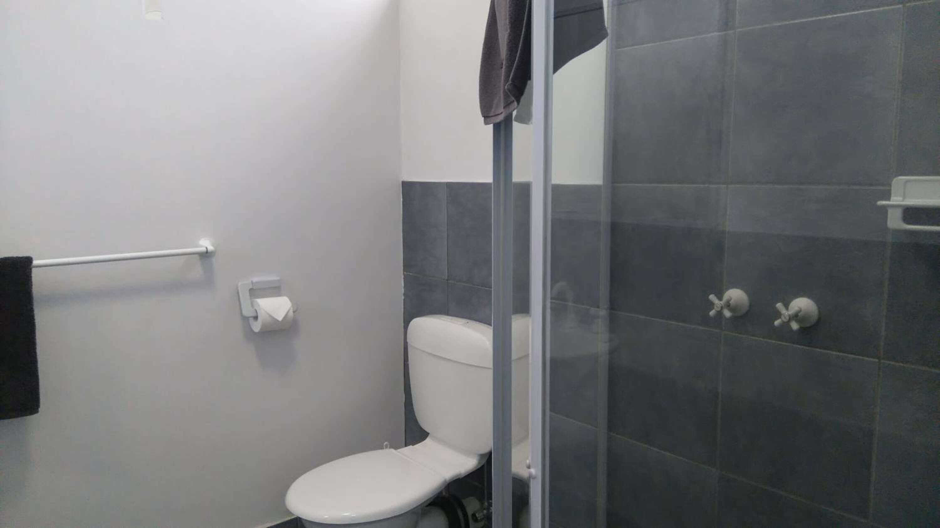 Une salle de bain équipée de toilettes, d’un porte-serviettes et d’un espace douche.