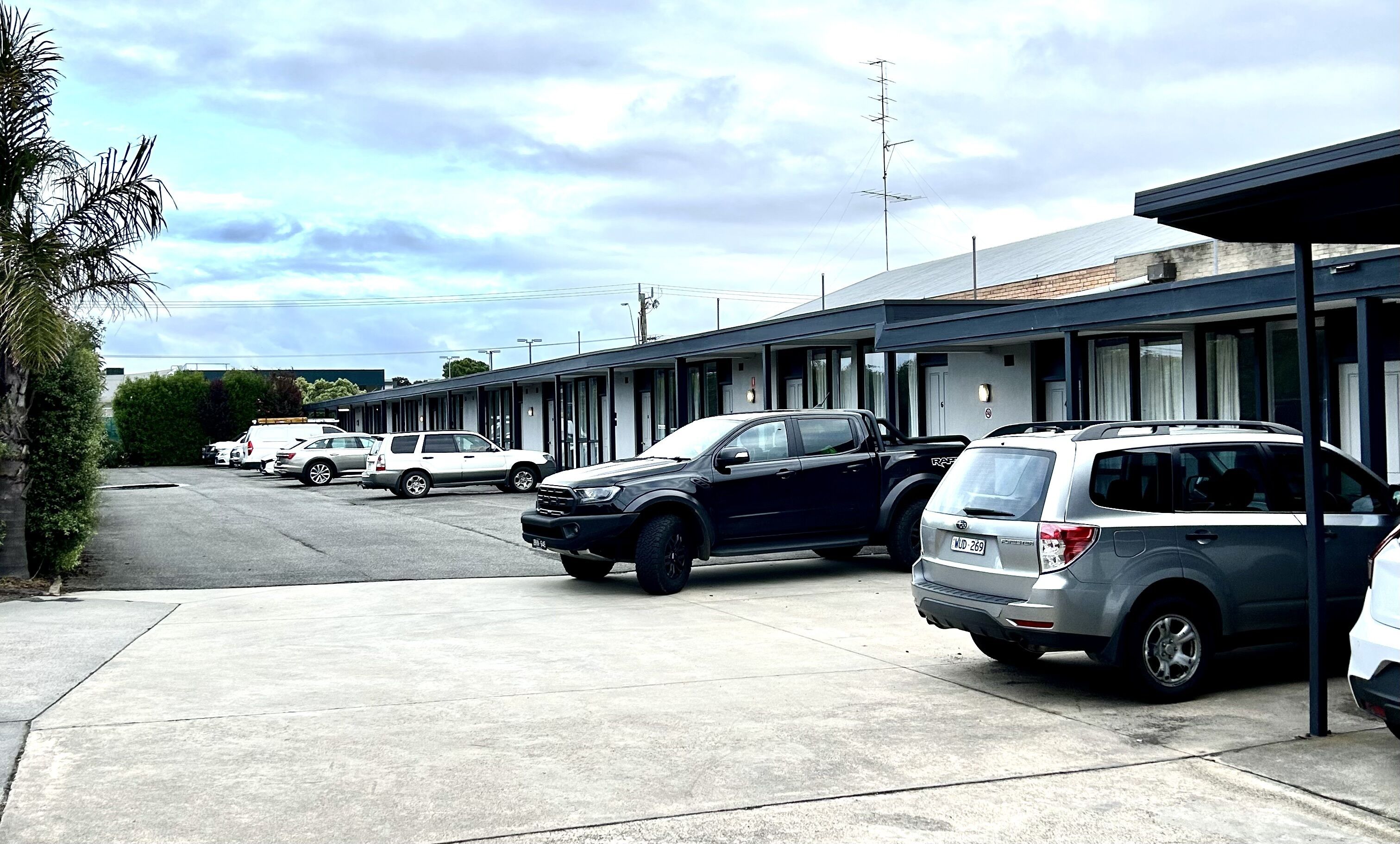 A motel with multiple parking spaces and a row of rooms.