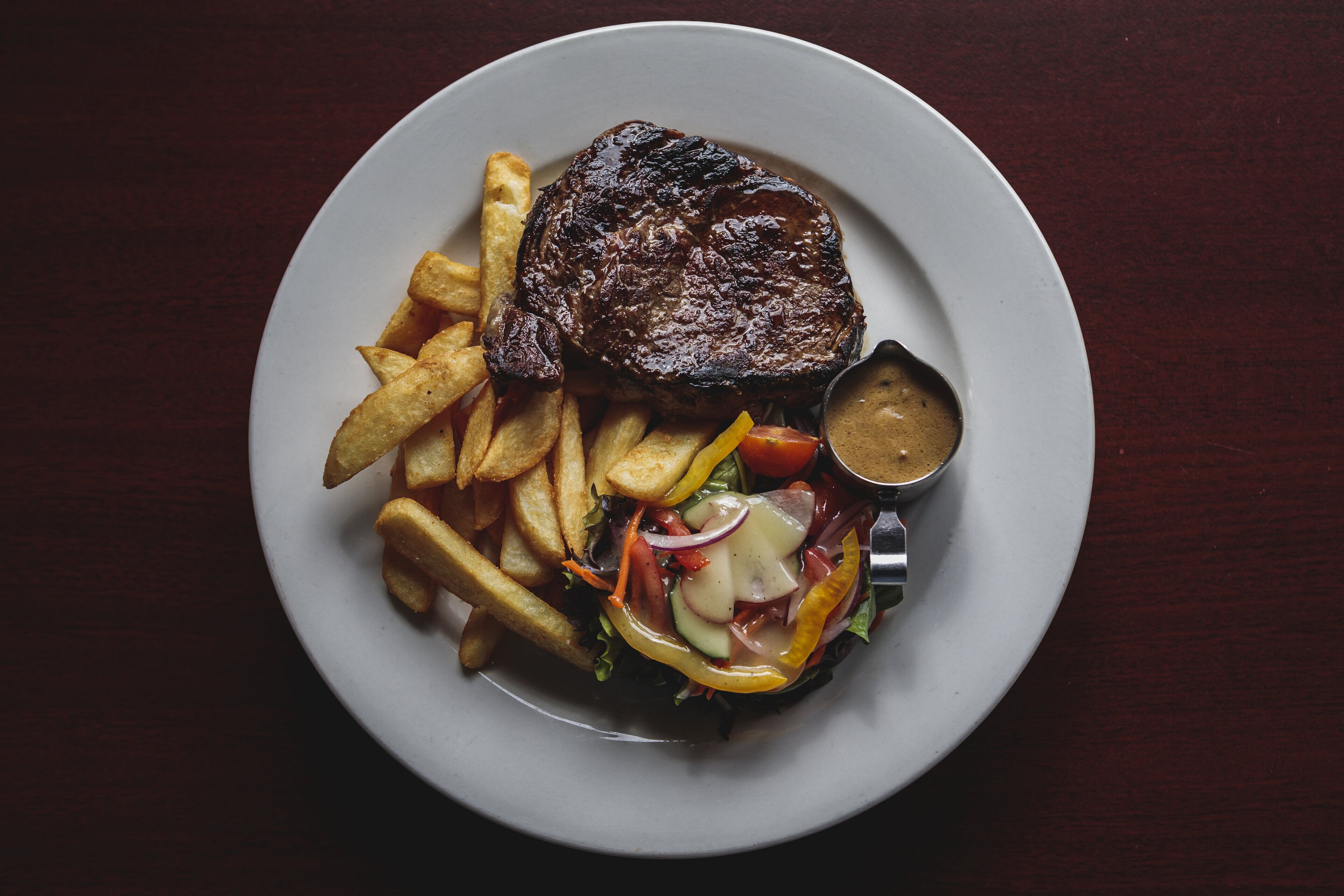 A plate with a steak, fries, and a salad.