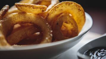 A bowl of onion rings with a side of dipping sauce.