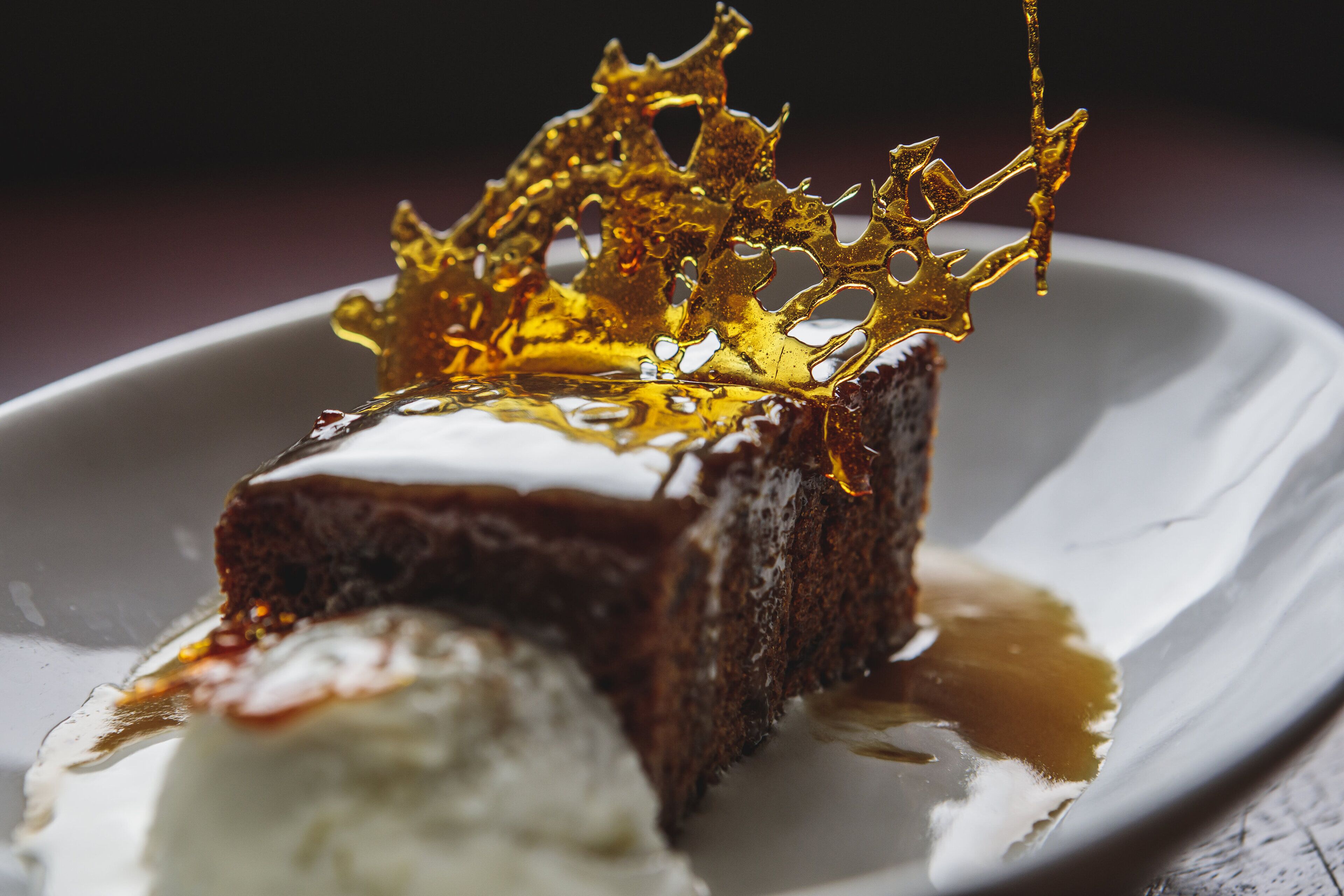 A dessert with a golden caramelized top and a scoop of ice cream on a white plate.