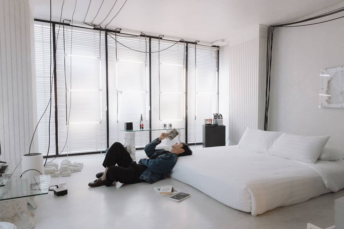 A modern bedroom with a large bed, a glass coffee table, and a desk with a chair.