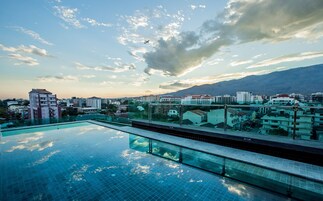 Una piscina al aire libre, sombrillas, sillones reclinables de piscina