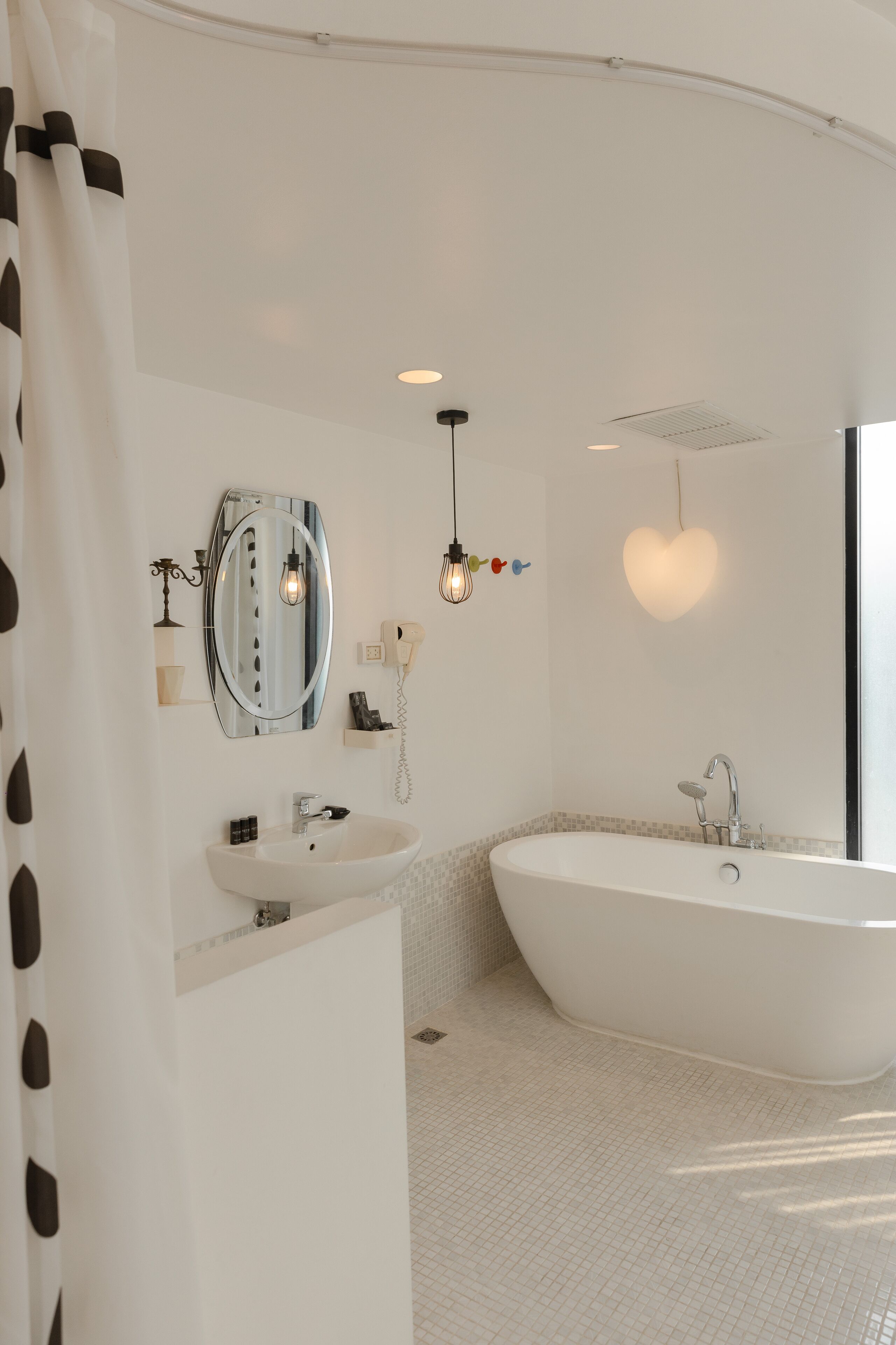 A modern bathroom with a freestanding bathtub, a vanity with a mirror, and a shower area.