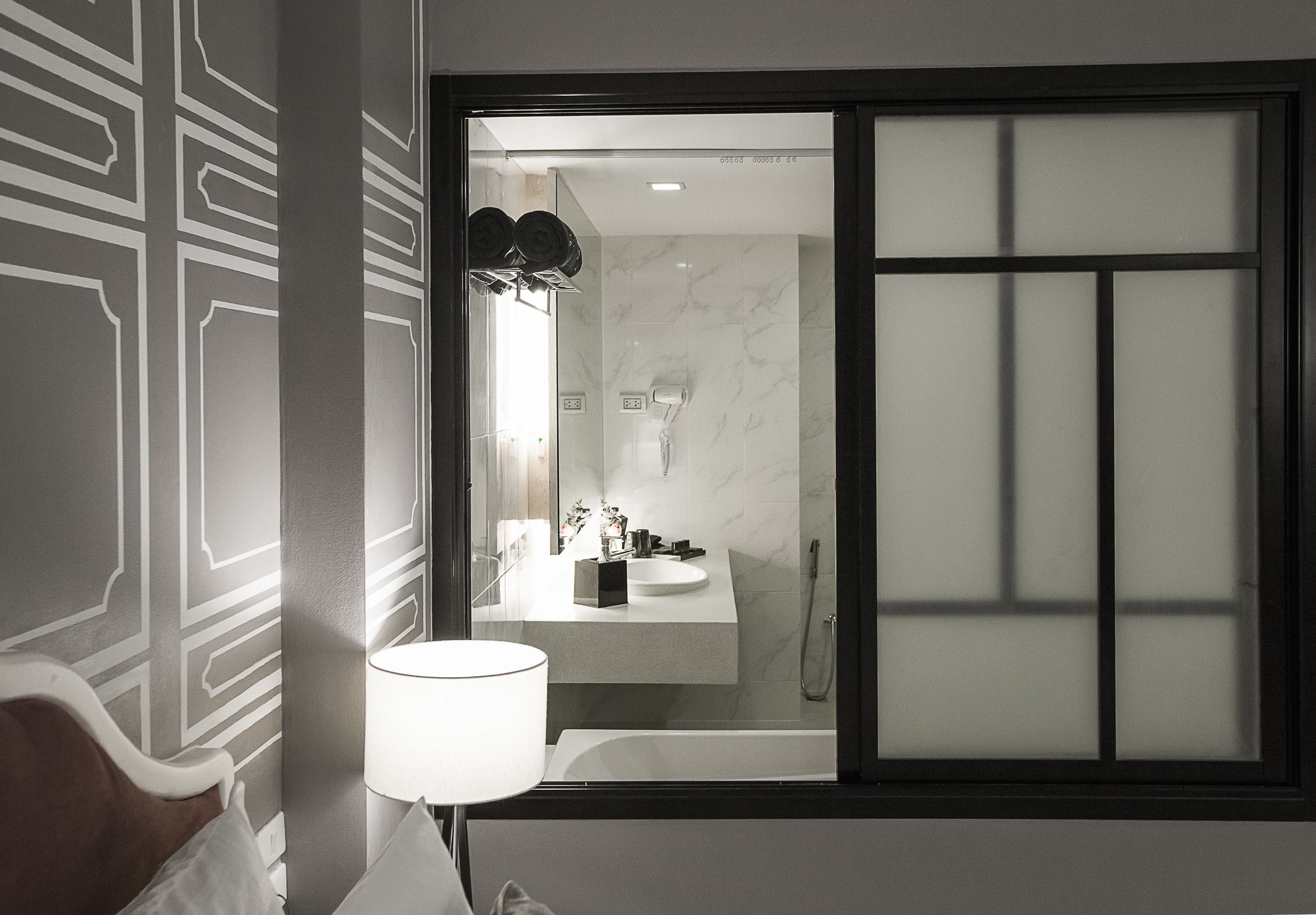 Un baño moderno con un espejo grande, un lavamanos y una bañera.