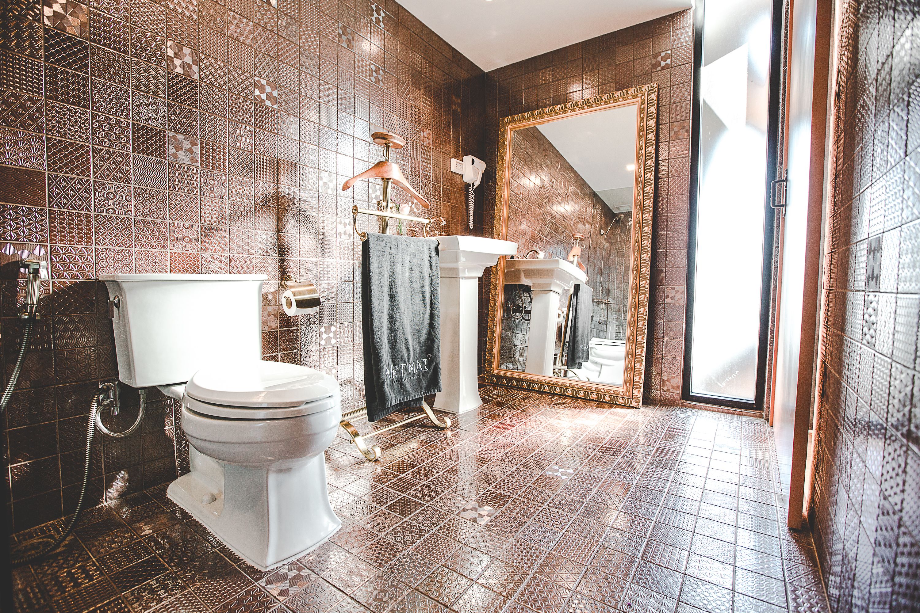 A bathroom with patterned tiles, a white toilet, a sink, and a large mirror.