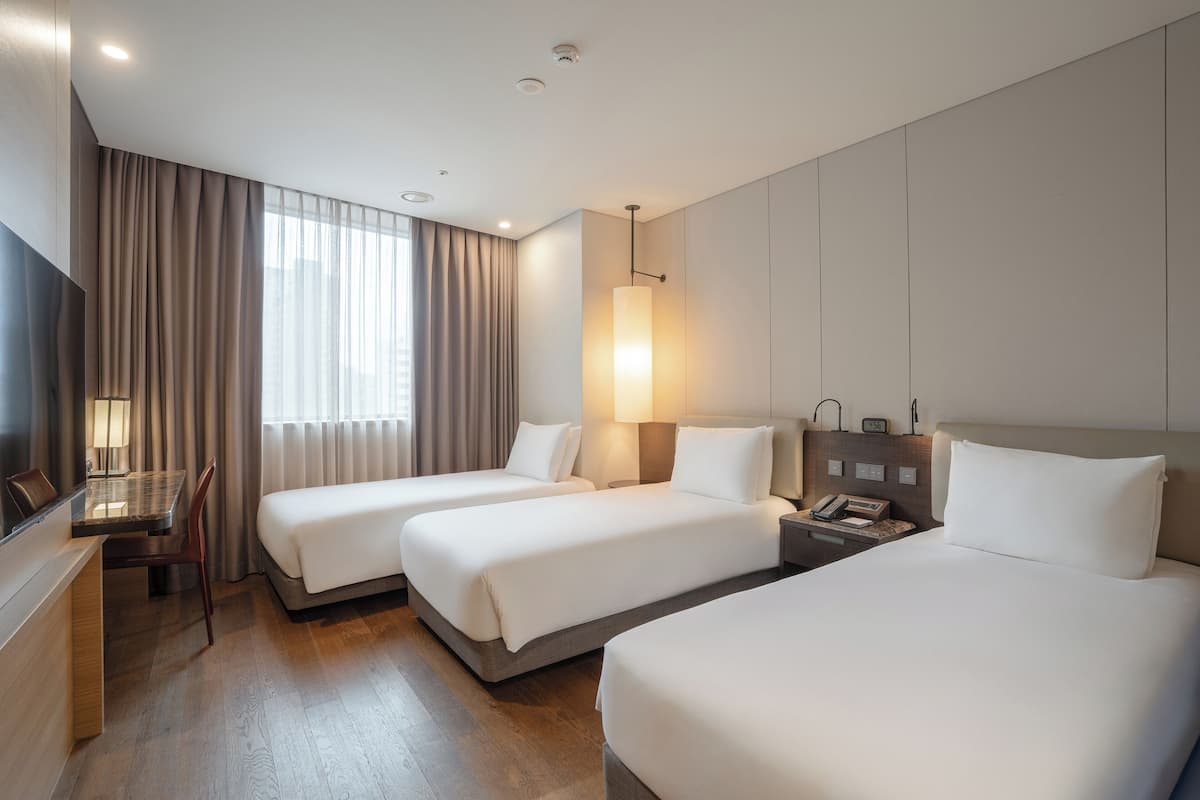A hotel room with two beds, a desk, and a chair.