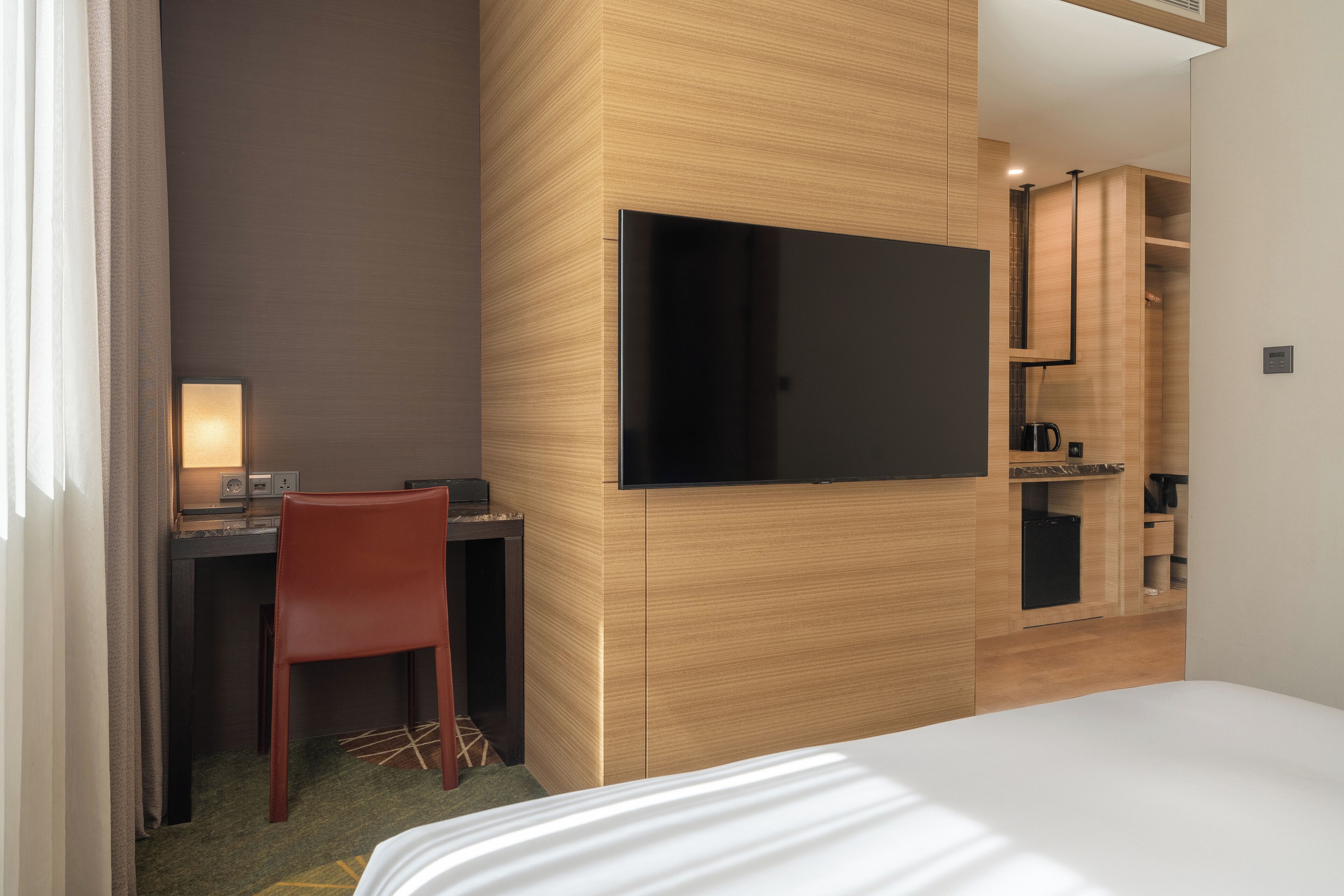 Une chambre d’hôtel comprenant un lit, un bureau avec une chaise, une télévision et une kitchenette.