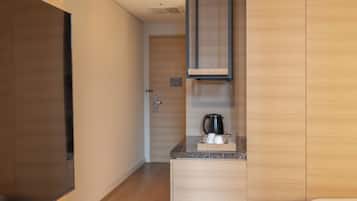 A modern kitchen with wooden cabinets, a marble countertop, and a coffee maker.