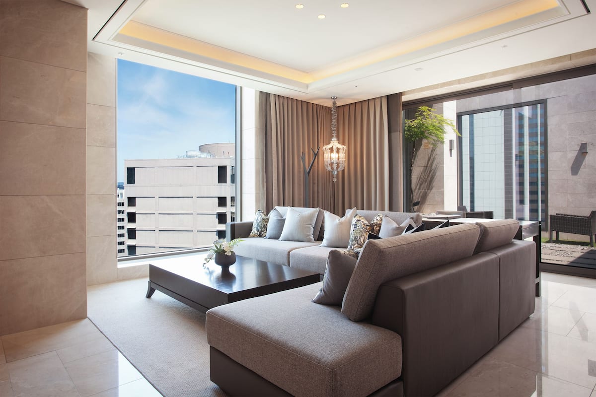 A modern living room with a sectional sofa, a coffee table, and a large window with curtains.