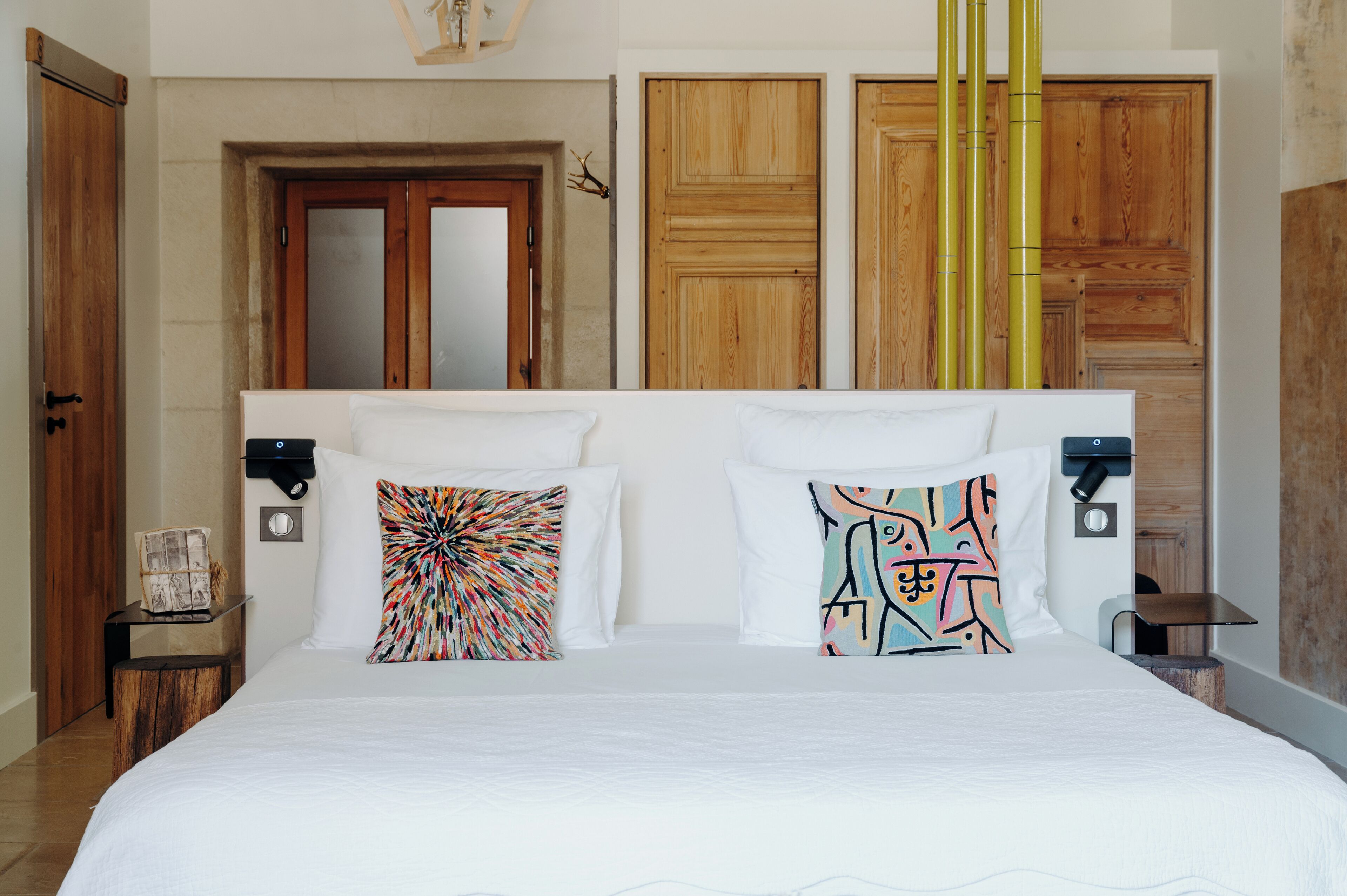 A bedroom with a large bed, two nightstands, a wooden wardrobe, and a mirror.