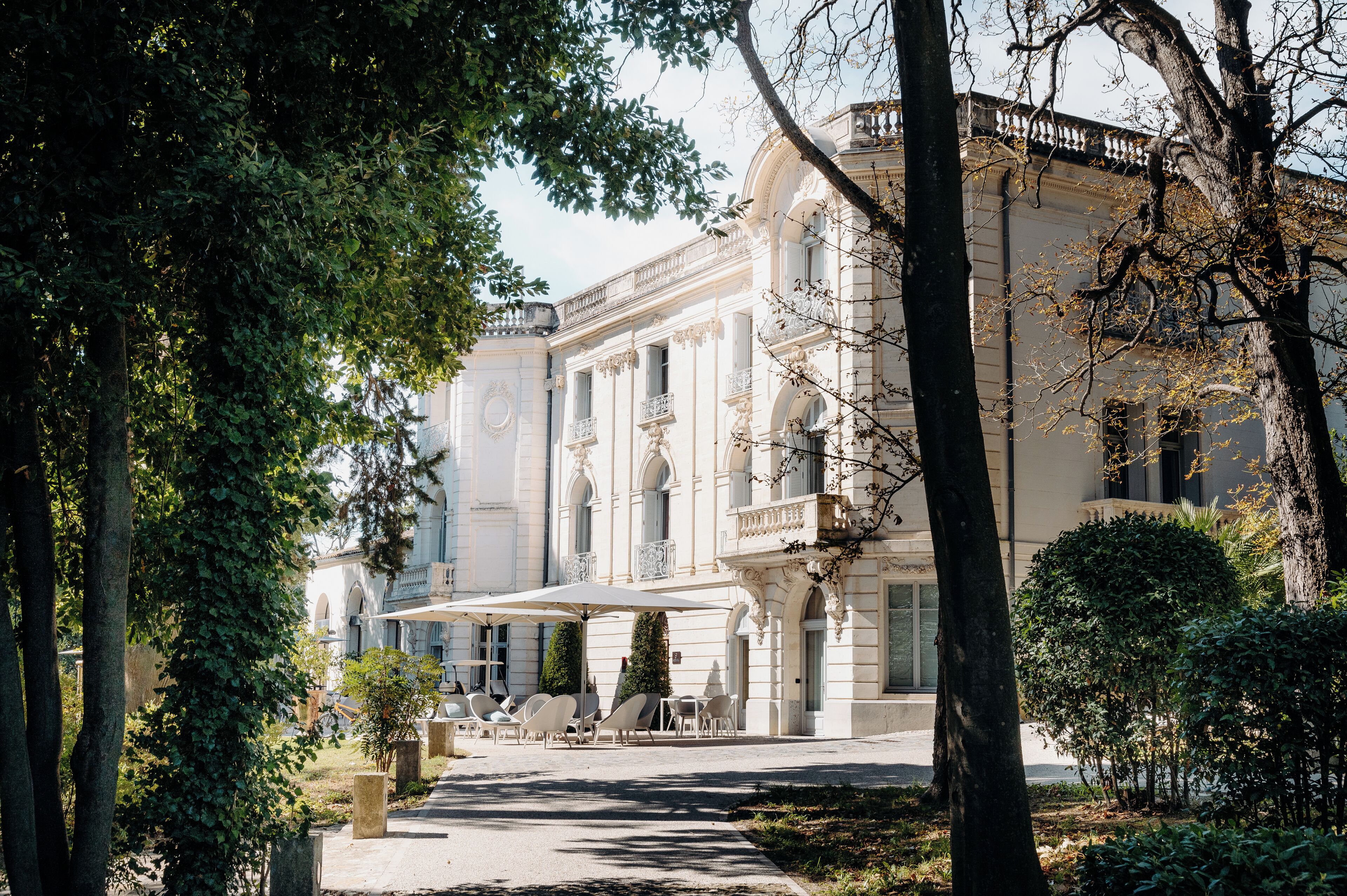 A classical building with a covered outdoor seating area and trees.