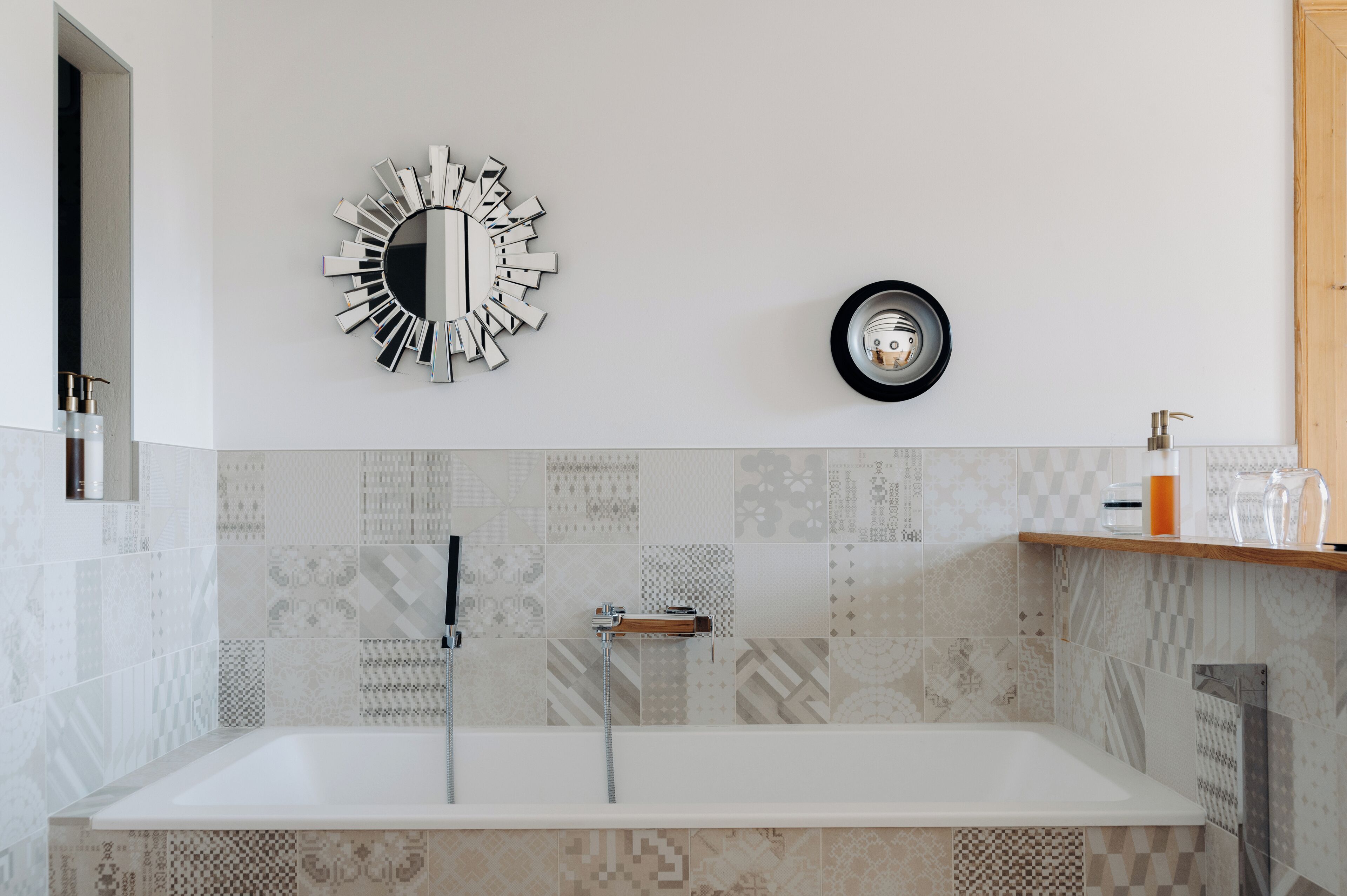 Une salle de bain moderne avec une baignoire sur pieds, un miroir fixé au mur et une horloge.