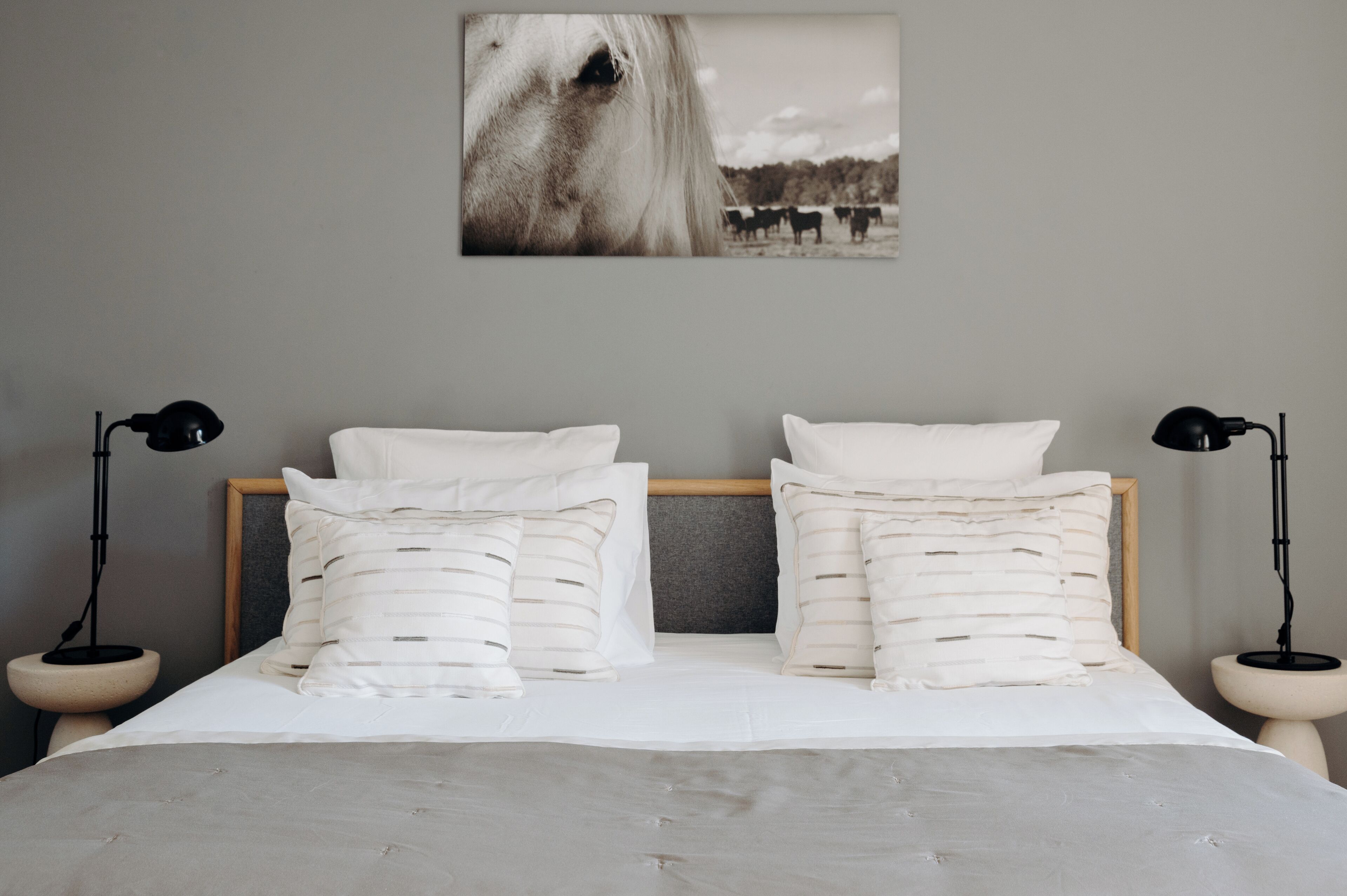 A bedroom with a wooden headboard, white bedding, and two bedside lamps.