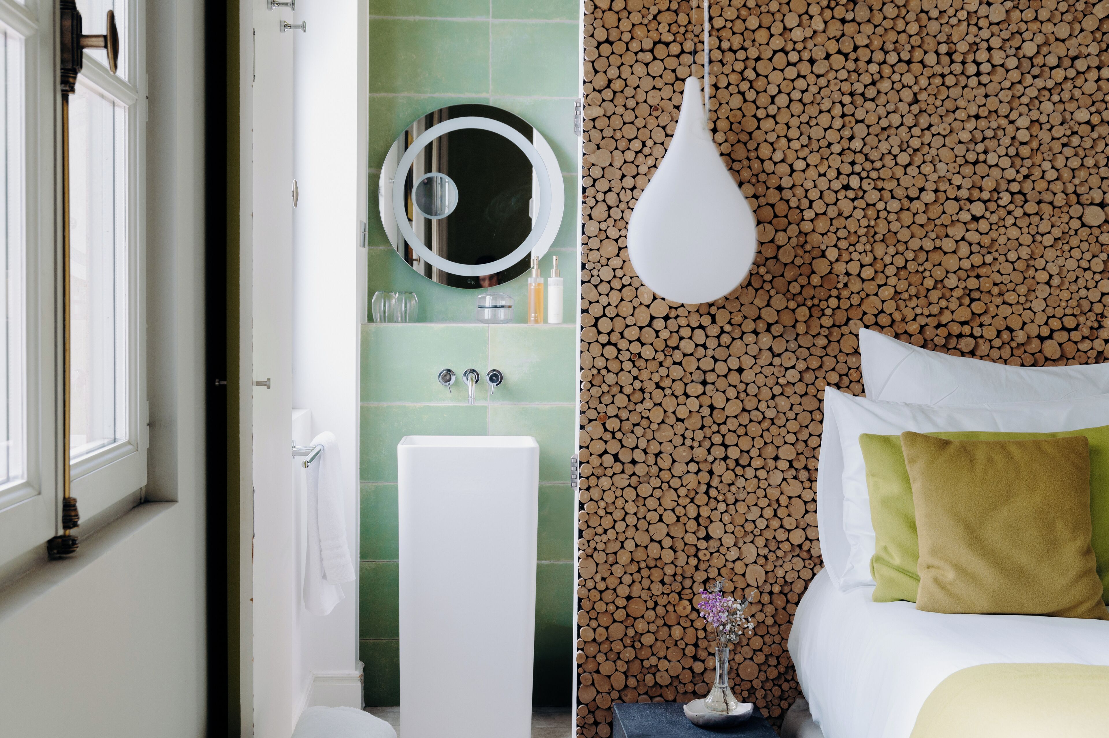 A bathroom with a toilet, sink, and mirror. The bathroom has green tiles and a white sink.