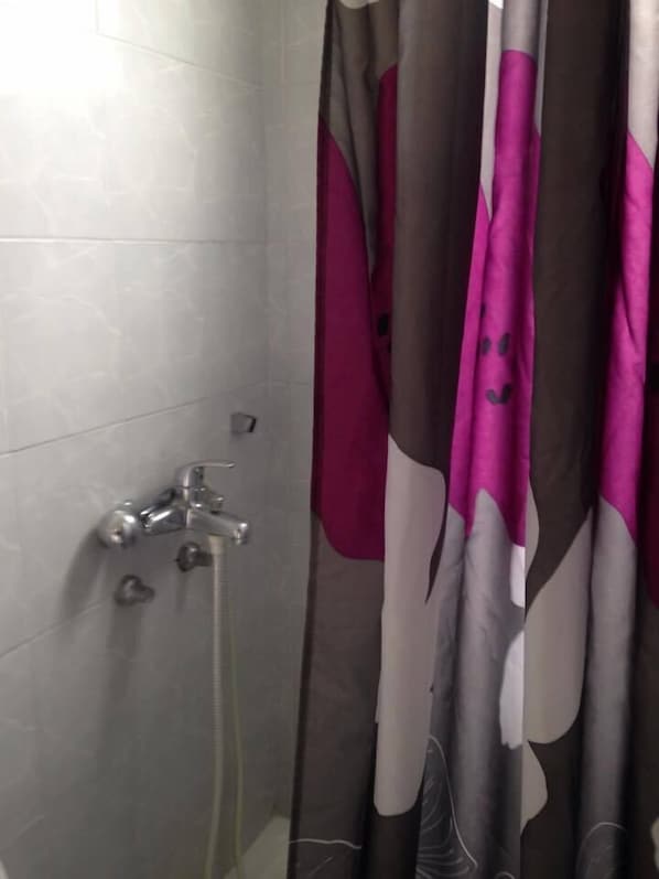 A shower area with a grey tiled wall, a silver faucet, and a showerhead. - Elpida Beach Studios (Rhodes)