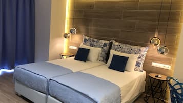 Una habitación de hotel moderna con una cama grande, mesitas de noche y un cabecero con iluminación integrada.