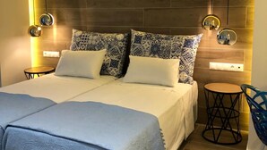 Een moderne slaapkamer met een groot bed, gestreepte kussens, een nachtkastje en een stoel.
