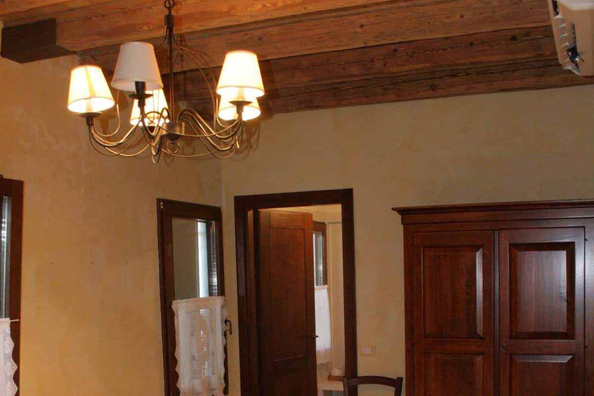 Ein Schlafzimmer mit einem großen Bett, Holzboden, einer Chandelüstere, einem Spiegel und einem Kleiderschrank.