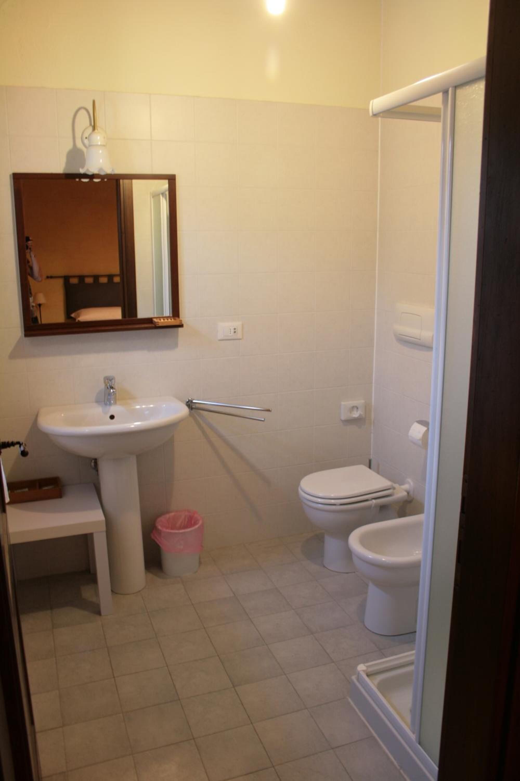 A bathroom with a sink, mirror, toilet, and shower.