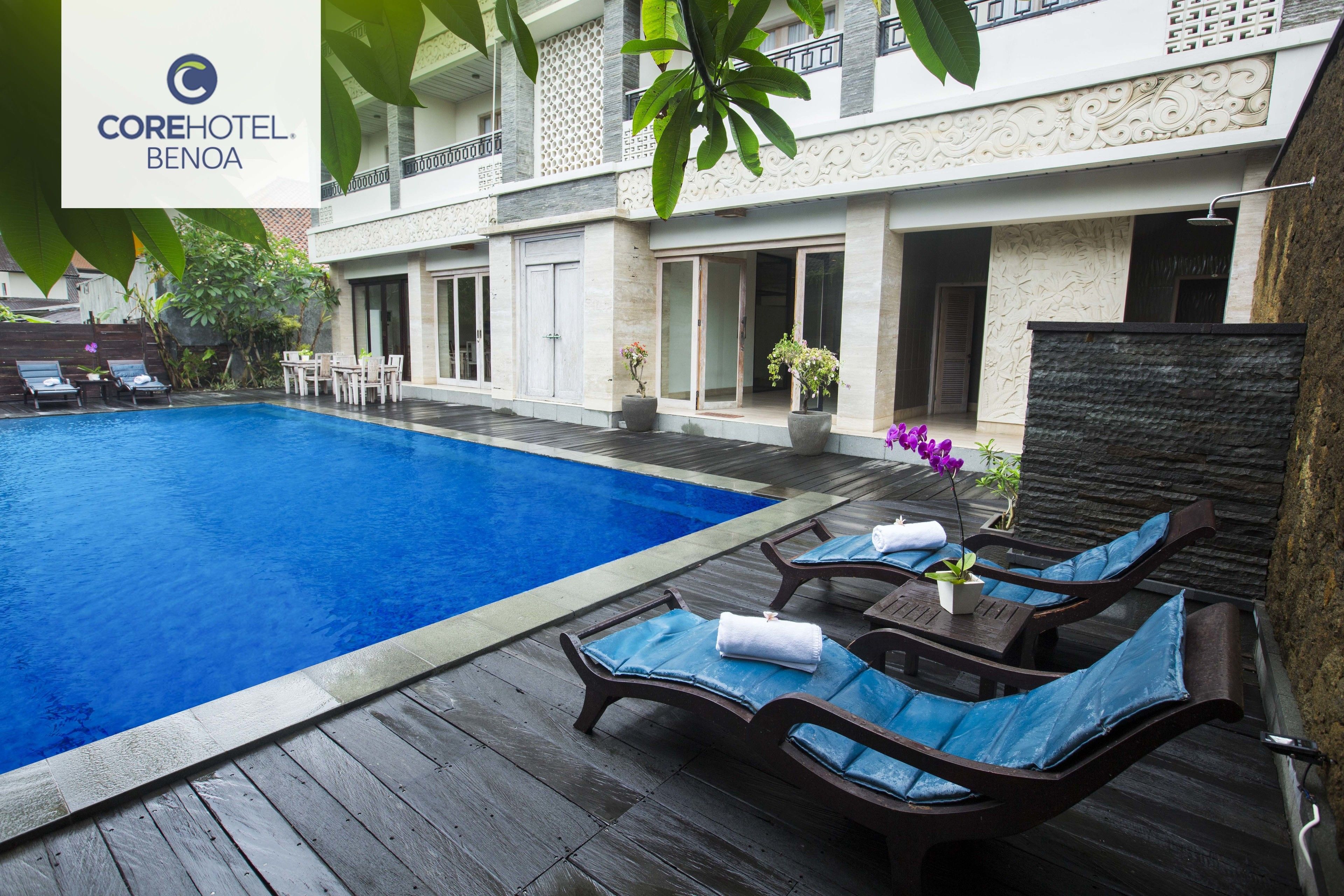 A pool area with lounge chairs and a stone wall.