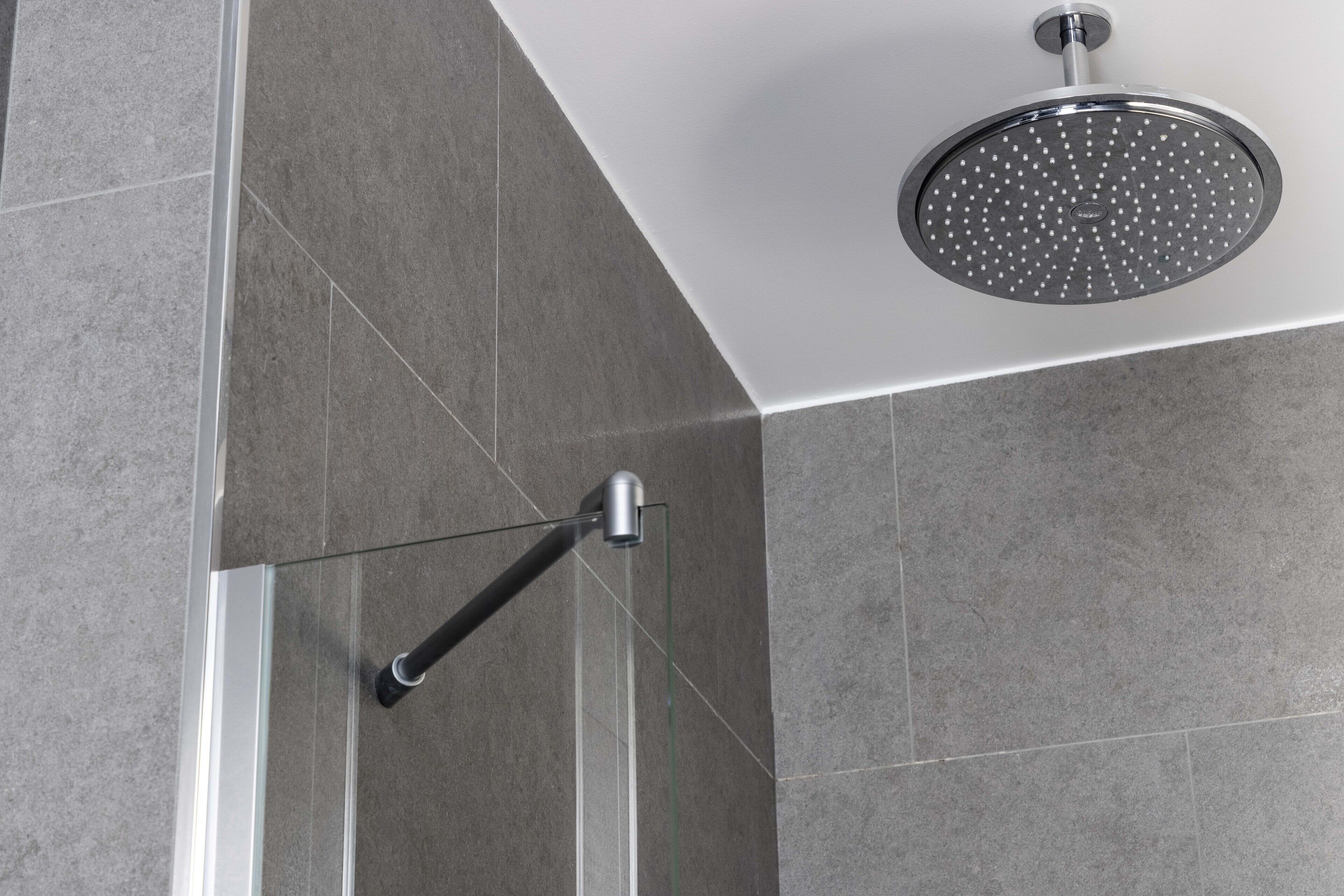 A shower with a circular head and a handheld showerhead.