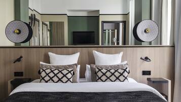 Ein Hotelzimmer mit einem großen Bett, zwei Nachttischen, einem Fernseher und einem Spiegel über dem Bett.
