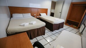 A hotel room with two single beds, a wooden wardrobe, a desk, and a chair. - Value Star Inn (Dagupan)