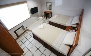 A hotel room with two beds, a desk, a chair, a TV, a mirror, and a window.