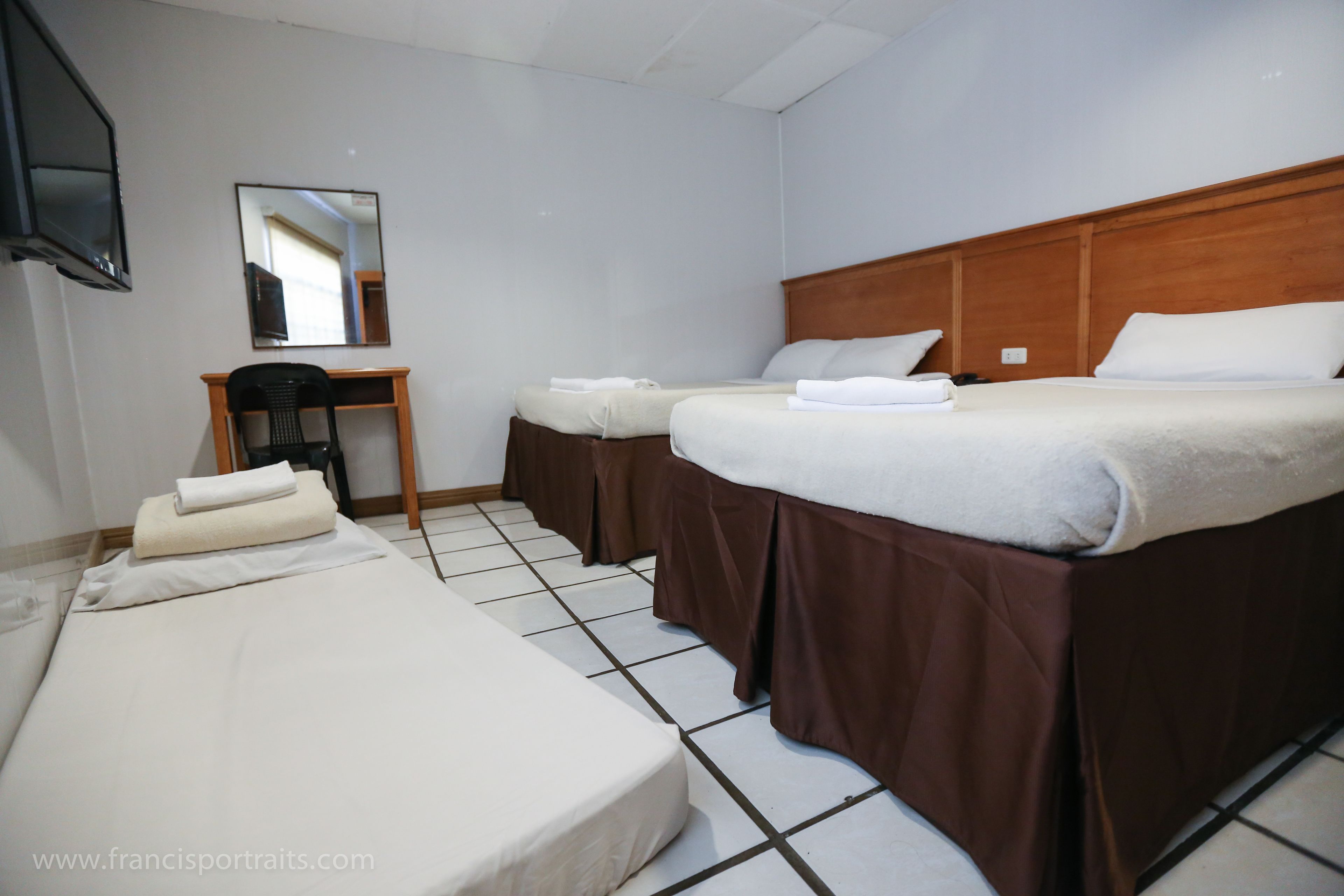 Une chambre d’hôtel avec deux lits, un bureau, une chaise et un téléviseur.